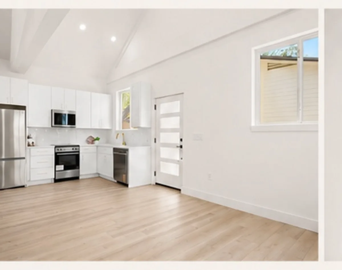 Finished ADU kitchen with white cabinets, stainless appliances, and vaulted ceiling
